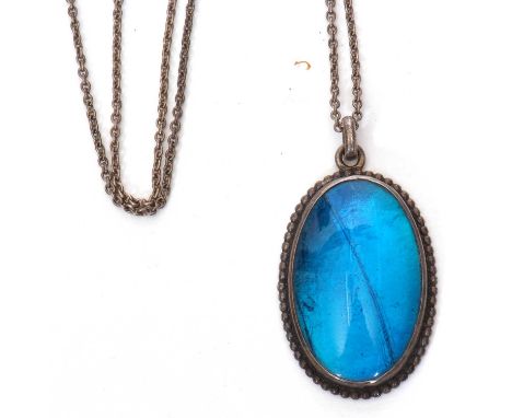Vintage white metal pendant of oval shape with a butterfly wing design under an oval glazed mount, the verso engraved 'Morpho
