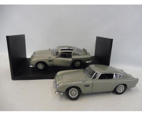 Two larger scale Aston Martin DB5s, some parts appear to be missing.