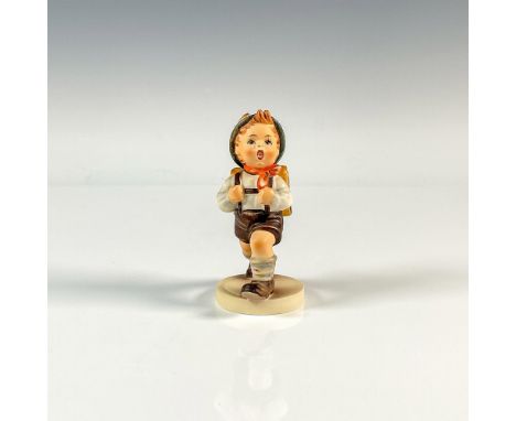 A matte figure of a boy dressed in lederhosen walking with his yellow backpack. Goebel backstamp. M.I. Hummel impressed. Issu