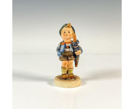 A colorful matte figure of a boy holding an umbrella under his arm and basket with a pig on his back. M.I. Hummel impressed. 