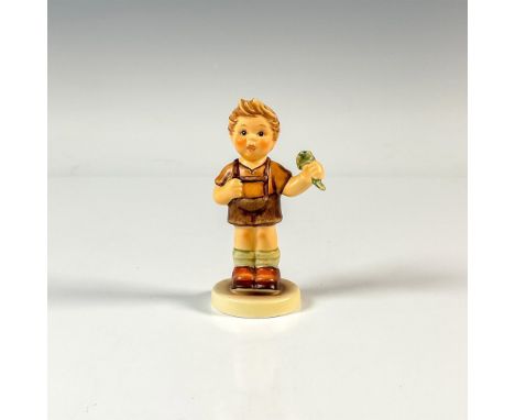 A figure of a boy in lederhosen holding a green plant for luck. First Issue 2003. M.I. Hummel impressed. Goebel backstamp. Is