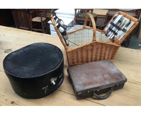A wicker picnic hamper with plates and flatware, together with a vintage leather hatbox, and a small leather gent's case 