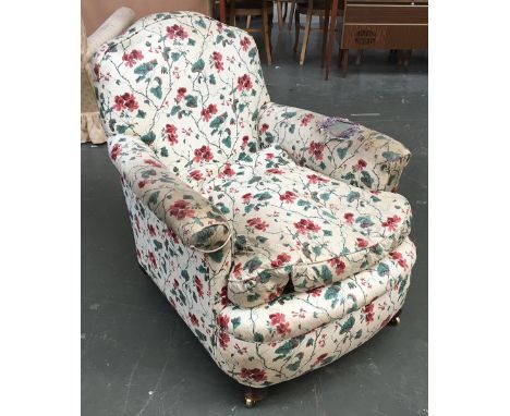 An armchair with outward scrolling arms, upholstered in a light floral print 