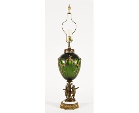 A tall decorative lamp, with bulbous glass body raised on a pedestal of three bronze effect cherubs on a marble and brass sty