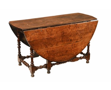 An 18th century walnut gate legged dining table, twin drop flap with frieze drawer and raised on turned legs with single gate