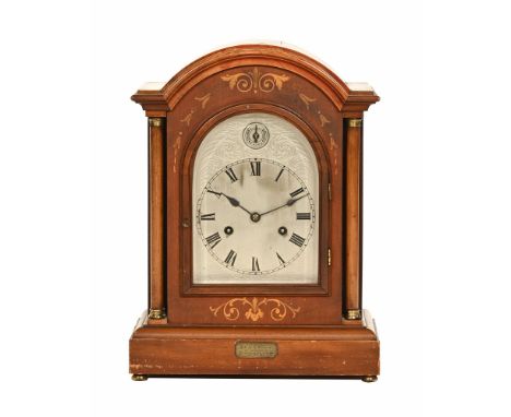 An Edwardian mantle clock, with domed top and inlaid case, with columns and silvered dial and plaque marked "Presented to Mr 