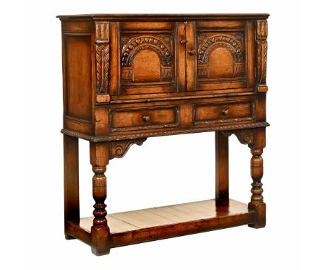 A Titchmarsh and Goodwin oak drinks cabinet, with moulded edge above a pair of carved panelled doors with shelves beneath and