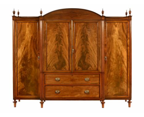 A late Georgian mahogany breakfront triple wardrobe, with series of finials to the detachable moulded cornice above a centre 