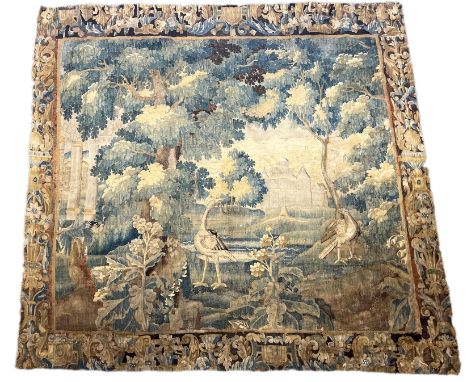 A 17th century Flemish Verdure tapestry depicting exotic birds in a landscape, a chateau beyond, within an urn and scrollwork