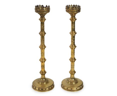 A pair of Victorian Gothic brass altar sticks with pierced foliate rims, knopped ring turned stems and paterae boss circular 