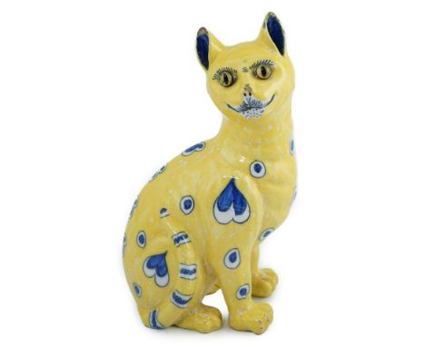 A Gallé yellow faience model of a seated smiling cat, c.1885, with applied glass eyes, decorated in blue with heart and teard