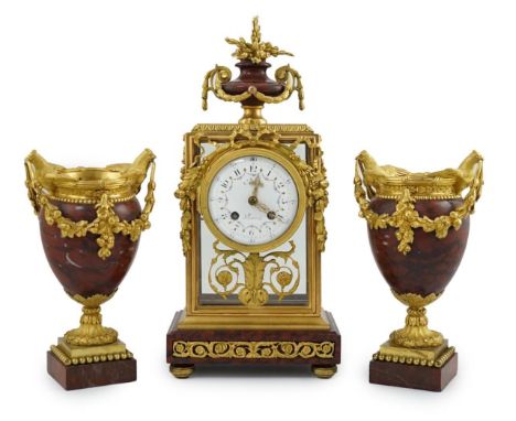 Revel à Paris. A 19th century French ormolu and rouge marble clock garniture, the mantel clock with urn finial and floral swa
