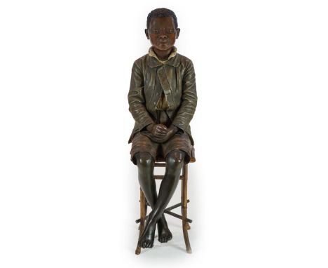 A late 19th century Friedrich Goldscheider life size cold painted terracotta figure of a black boy seated upon a bamboo and w