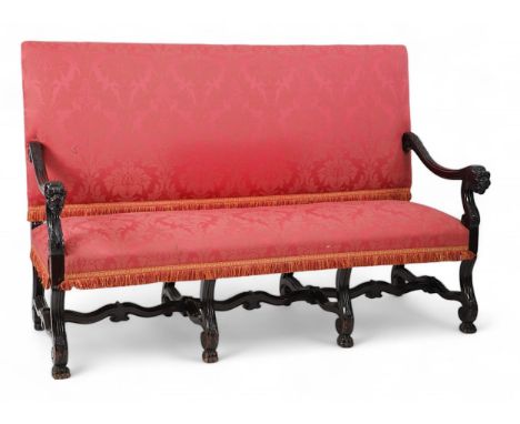 A 17th century style walnut settee with upholstered back and seat, acanthus carved scroll arms with lion's head terminals on 