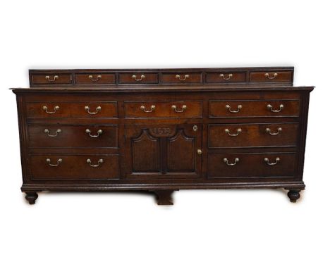 A George III oak dresser base, the raised back with six crossbanded drawers over three frieze drawers and central cupboard fl