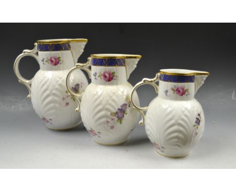 A set of three Coalport graduated Caughley Mask-Head jugs, printed with summer flowers, the largest 20cm high