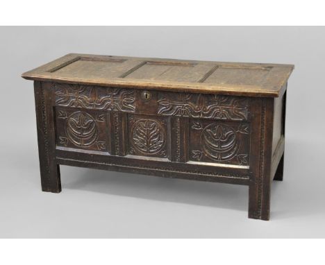 A LATE 17TH CENTURY WEST COUNTRY OAK COFFER, with a three panel lid with pin hinges, the front with a deep top frieze carved 