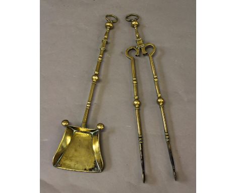 A PAIR OF 18TH CENTURY BRASS FIRE IRONS, the shovel with broad blade and 'button' decoration to the corners, on a decorated s