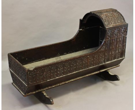 A CHARLES II STYLE CARVED OAK CRADLE, the rocking cradle of traditional form with arched canopy and all over repeated decorat