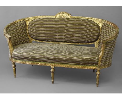 A LOUIS XVI STYLE GILTWOOD SETTEE, with rounded arms and leaf carved gilt frame surmounted by a scrolling and floral carved r