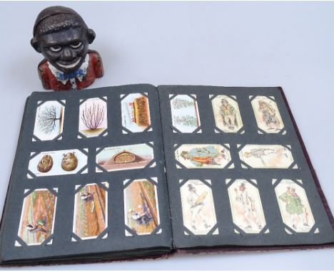 An album of cigarette cards, and a Vintage cast-iron money bank, height 4.5" 