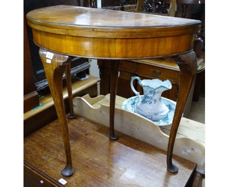 A 1930s cross-banded walnut fold over card table, raised on cabriole legs, W80cm 