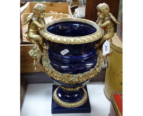 An ornate ceramic and brass-mounted urn with cherub mounts, overall height 14" 