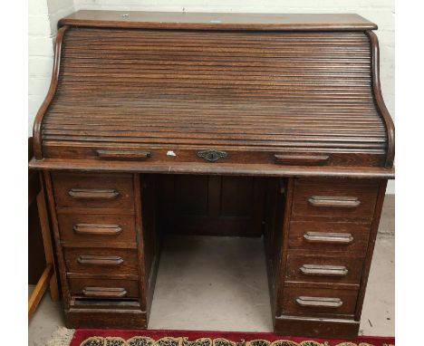An early 20th century oak "S" scroll roll top desk by Globe Wernicke with filled interior and 8 pedestal drawers (central fri