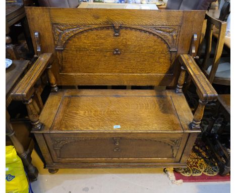 A carved oak Monks Bench with hinged storage compartment.
