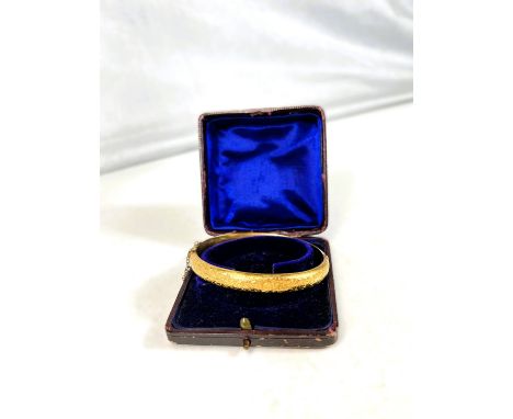 A 15ct hallmarked gold hinged bangle with chased acanthus decoration (some dents) 11.5grams.