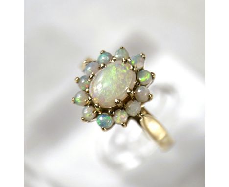 A dress ring set with central oval white opal surrounded by a band of small white opals, the stones with bright flashes visib