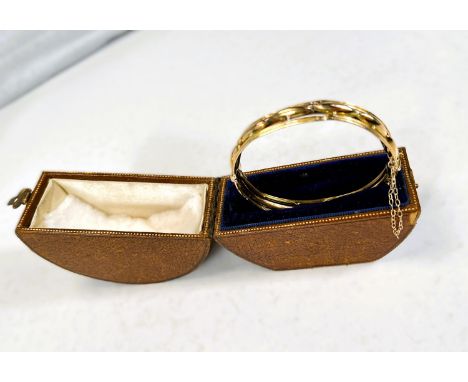 A yellow metal hinged bangle with reeded oats rim and lozenge shaped central section, stamped 15 carat, 15gms