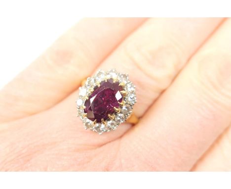 Ruby and diamond cluster ring, the oval cut ruby of approx. 1.5cts, measuring 11mm x 6mm, in yellow gold claw mount, bordered