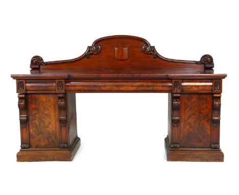 Victorian mahogany twin pedestal sideboard, circa 1870, having a carved panel back centred with a vacant shield, over an inve