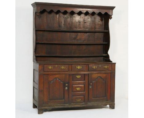 Late George II oak dresser and rack, North Wales, circa 1750, having a moulded cornice over a pot bellied plate rack, the bas