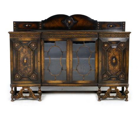 George V oak display sideboard, in Jacobean Revival style, having a back panel over two central glazed doors opening to a sin