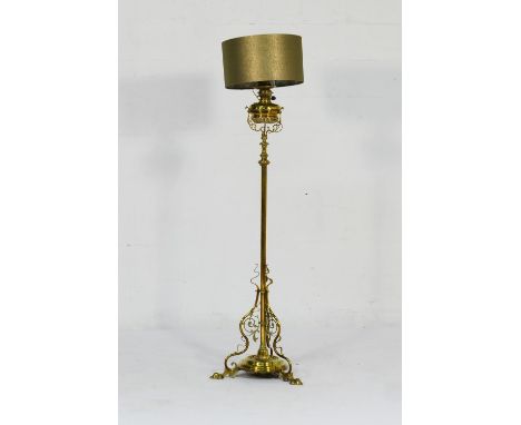 Late Victorian brass standard lamp, having a brass tank over an extendable column, the base with three scroll bracket support