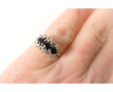 Sapphire and diamond cluster ring, three round cut sapphires bordered with small round brilliant cut diamonds, all set in 18c