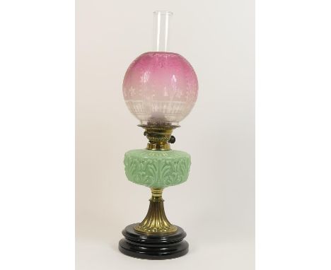 Victorian pedestal oil lamp, having a cranberry tinted and etched globular shade over a moulded green glass tank and fluted c