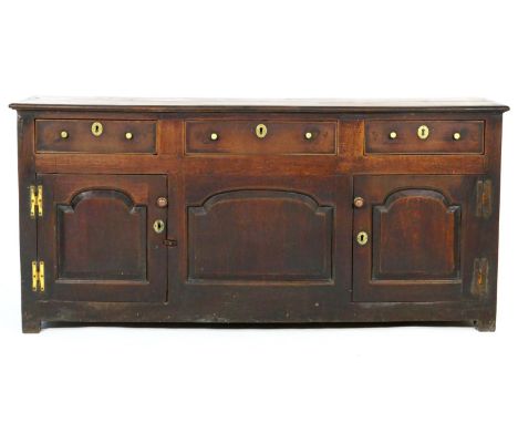 George II oak enclosed dresser, North Wales, circa 1740-60, having a two plank top over three short drawers with later brass 