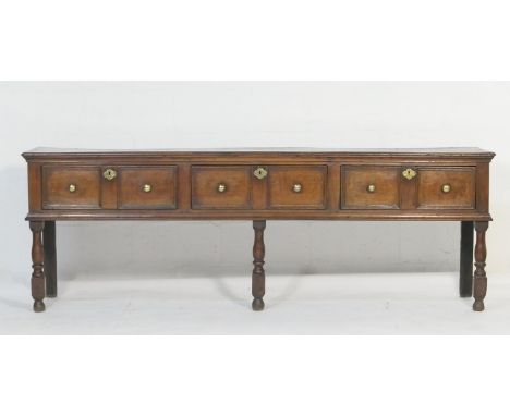 Oak low dresser, circa 1700-20, two plank top over three double moulded panel drawers with engraved brass escutcheons and lat