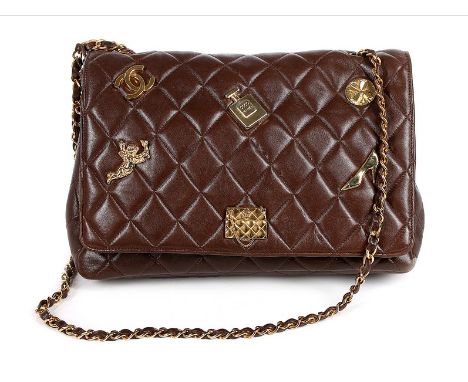 A Chanel quilted brown leather shoulder bag, 1990s, the front closure applied with Chanel insignia plaques including perfume 