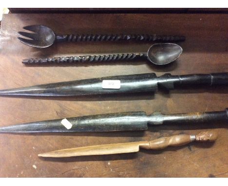 Three ethnic wooden daggers and a large carved wooden spoon and fork