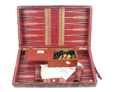 A vintage games board and chess pieces. The games board bound in red leather, opening to reveal a backgammon board, together 