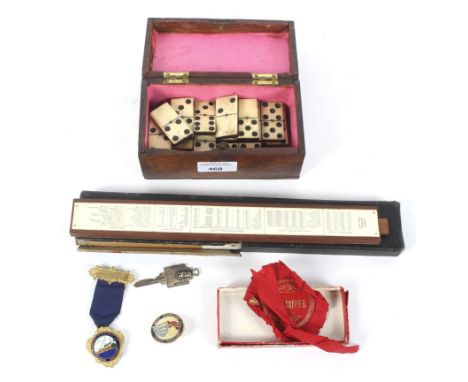 An assortment of collectables. Including a set of bone and ebony dominoes, a sliding rule, enamel badges and medals, etc
