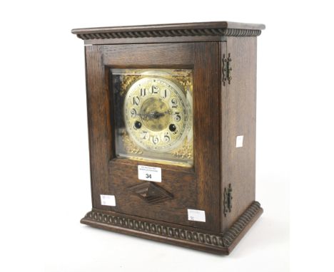 A late 19th century mantel clock. The brass dial with Arabic numerals, the oak case of rectangular form with carved details a