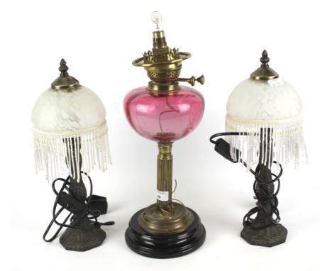 Three table lamps. Comprising: a pair of bronzed metal lamps with palmettes and beaded domed glass shades, a converted Victor