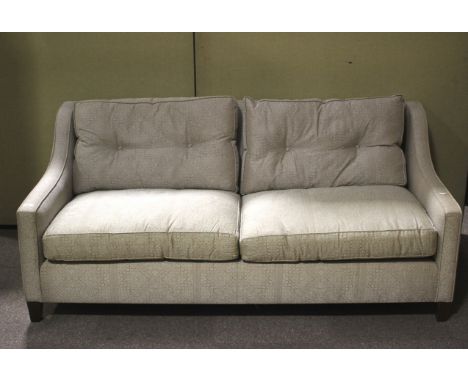A contemporary two seater sofa. With curved armrests and button back cushions, upholstered in patterned blue and gold fabric,