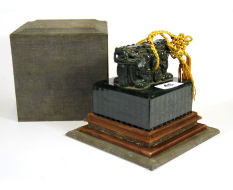 A fine Chinese hand carved jade seal mounted with a two headed lion and resting on a wooden stand with cover, H. 14cm.