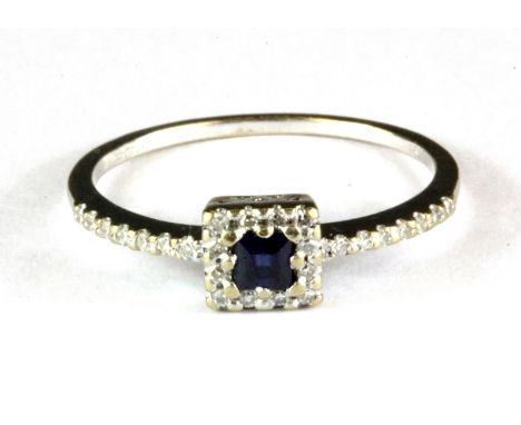 An 18ct white gold ring set with a step cut sapphire and diamonds, (O).